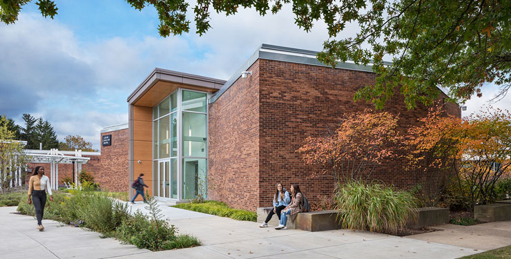 Students walking in front of the exterior of the General Classroom Building at Penn State University.