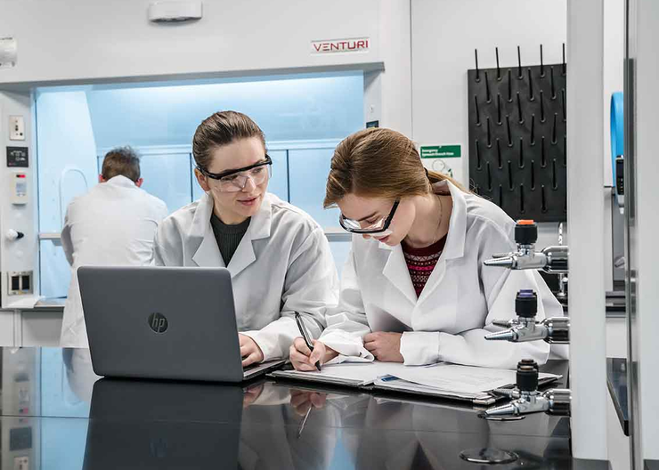 Two students share a computer while in a lab setting