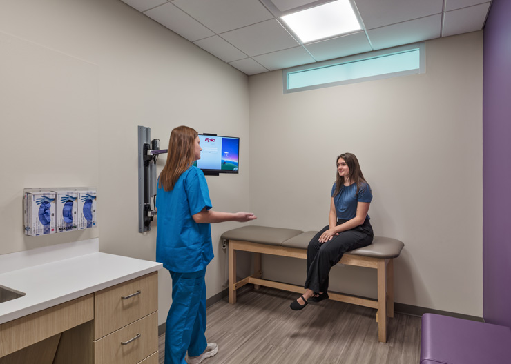 inside of one of the patient rooms with a bed at the far back wall and the doctor's counterspace on the left