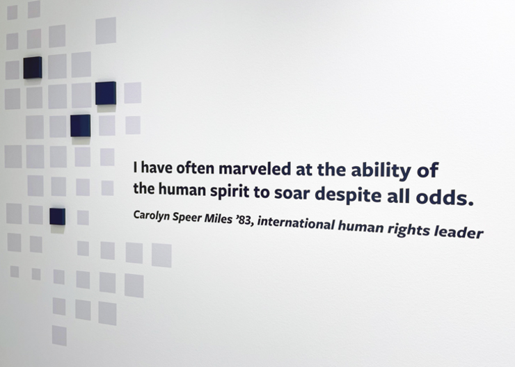 A blue alumni quote is displayed on a white wall