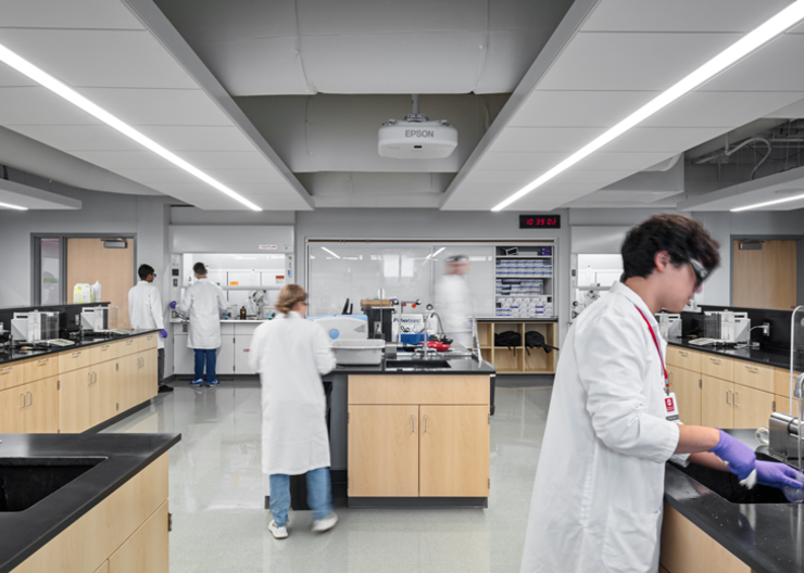 Chemistry students gather around work areas while performing labs