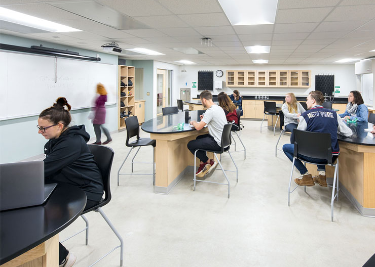 Students look toward the front of the lab at their teacher
