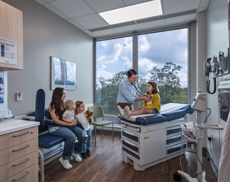 image of an examination room with mom, children, and doctor