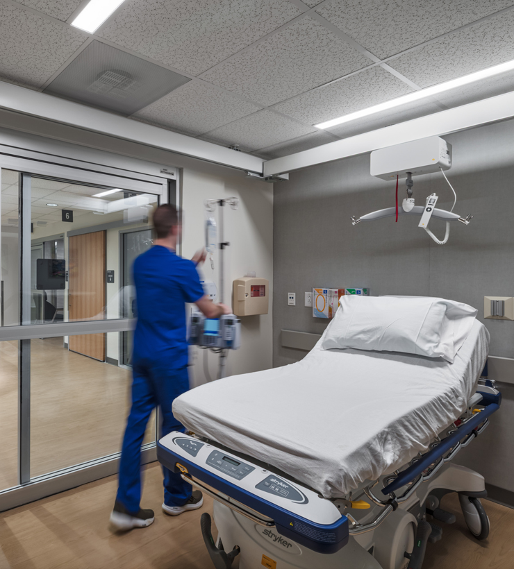 Nurse in room and people talking at desk