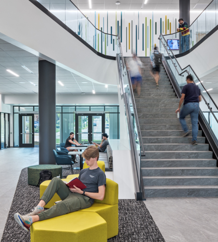 A student reads at the bottom of a grand staircase