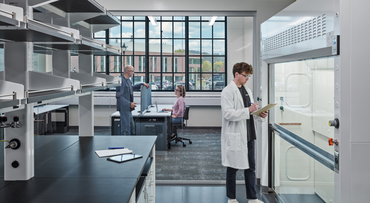 A researcher stands inside a lab with a transparent glass wall