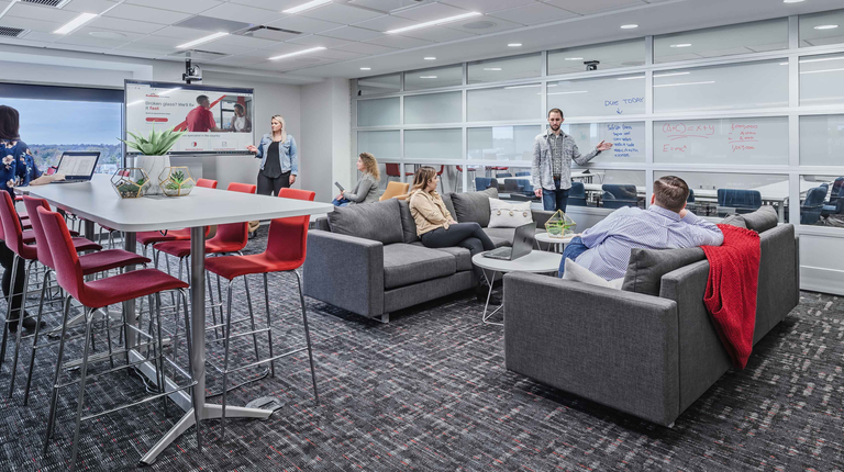 Employees gather together on couches and bar seating to use the flexible collaboration space