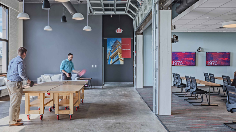 Employees play ping pong on one side of Schaefer's common area, and two employees are on the other side in the training center
