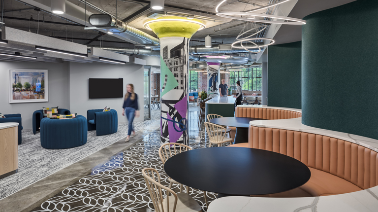 The Talent Magnet is furnished with plenty of comfy seating space and tables. Columns throughout the space add a pop of color to the muted space.