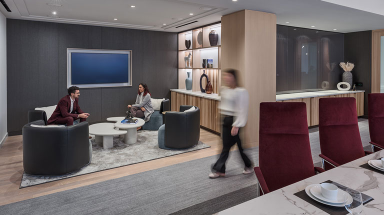 two people talking in lounge with someone walking by