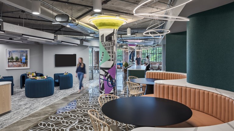 A work environment features booth seating and a large column covered in colorful graphics