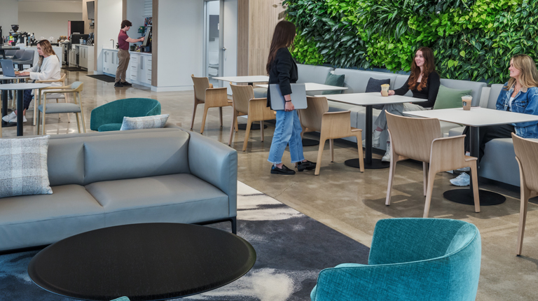 Employees gather in a collaboration area that is backed by a large living wall