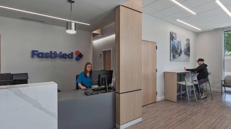 entrance to the new fastmed urgent care with a front desk on the left and a waiting area with tables on the right