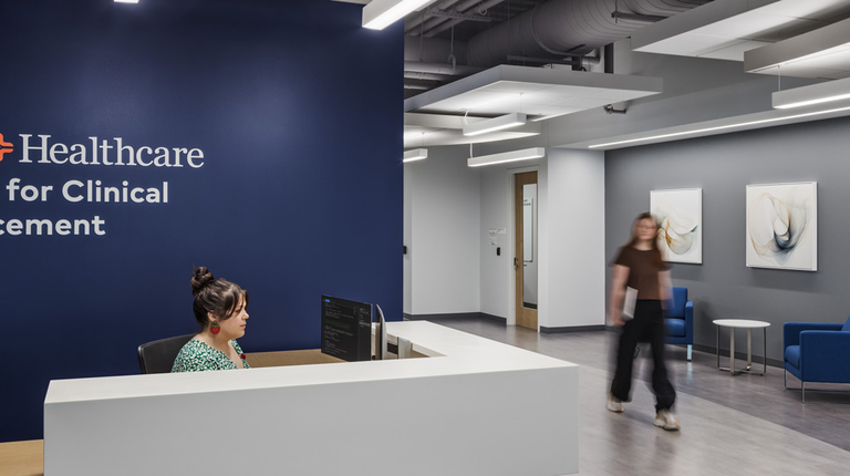 Reception area for HCA Healthcare's Center for Clinical Advancement, with a receptionist at the front desk and abstract artwork lining the hallway.